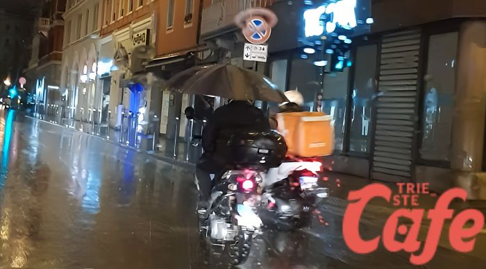 Pioggia in largo Barriera, in scooter con l'ombrello 