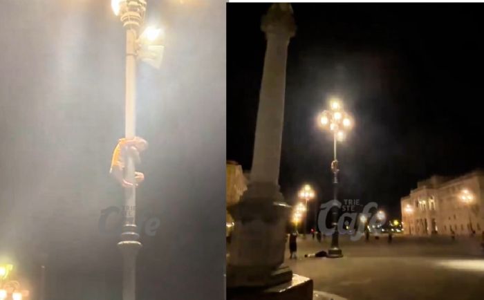 Scena surreale in piazza Unità: uomo si arrampica su un lampione davanti ai passanti increduli (VIDEO)