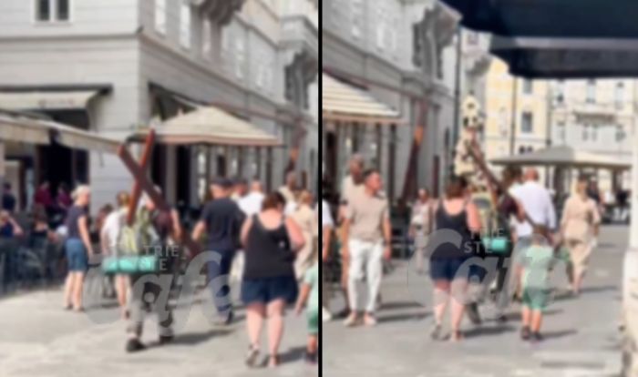 Cammina con una grande croce in spalla nel cuore di Trieste: stupore tra i passanti in piazza Unità